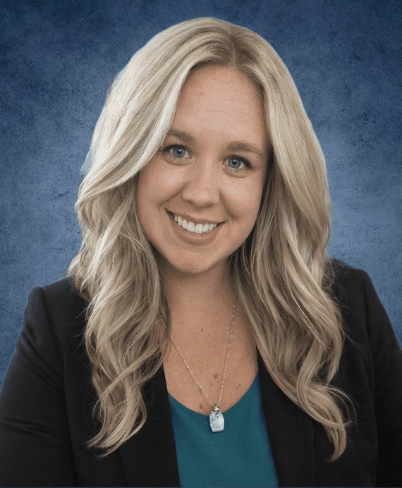 Smiling blonde woman in blazer against blue background