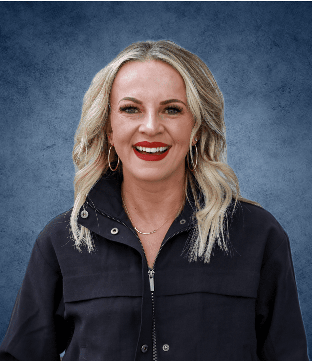Smiling blonde woman in dark jacket, blue background